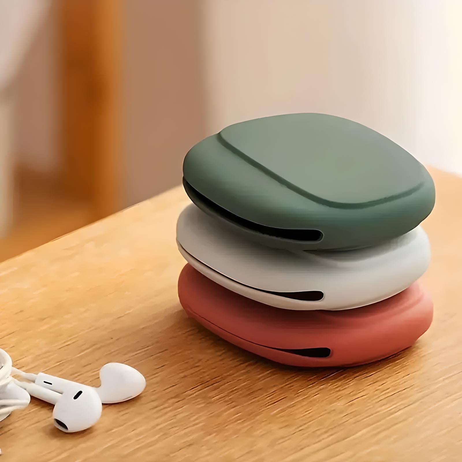 Stacked wireless earbuds cases in green, white, and pink on a wooden table, with white earbuds nearby. Modern tech accessories, minimalist design.