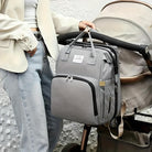 Stylish gray diaper bag backpack attached to a stroller, featuring multiple compartments, durable fabric, and modern design for convenient parenting.