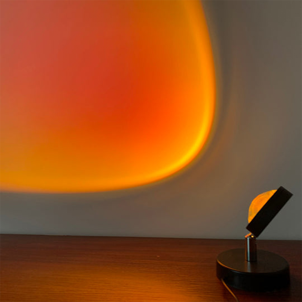 Modern sunset projection lamp casting warm orange and red hues on a wall, creating a cozy ambiance. Ideal for home decor and mood lighting.