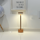 Modern copper LED table lamp on white countertop, illuminating a minimalist space with a globe and motivational wall art. Stylish home decor lighting.