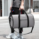 Man holding a stylish gray duffel bag with black straps, wearing casual streetwear and white sneakers. Perfect for travel, gym, or sports use.