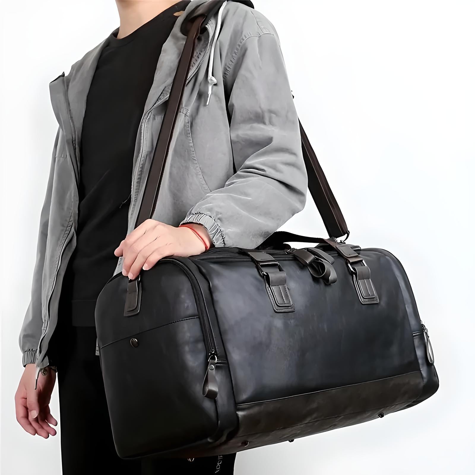 Man carrying a stylish black leather duffel bag with shoulder strap, wearing a gray jacket. Perfect for travel, gym, or weekend trips.