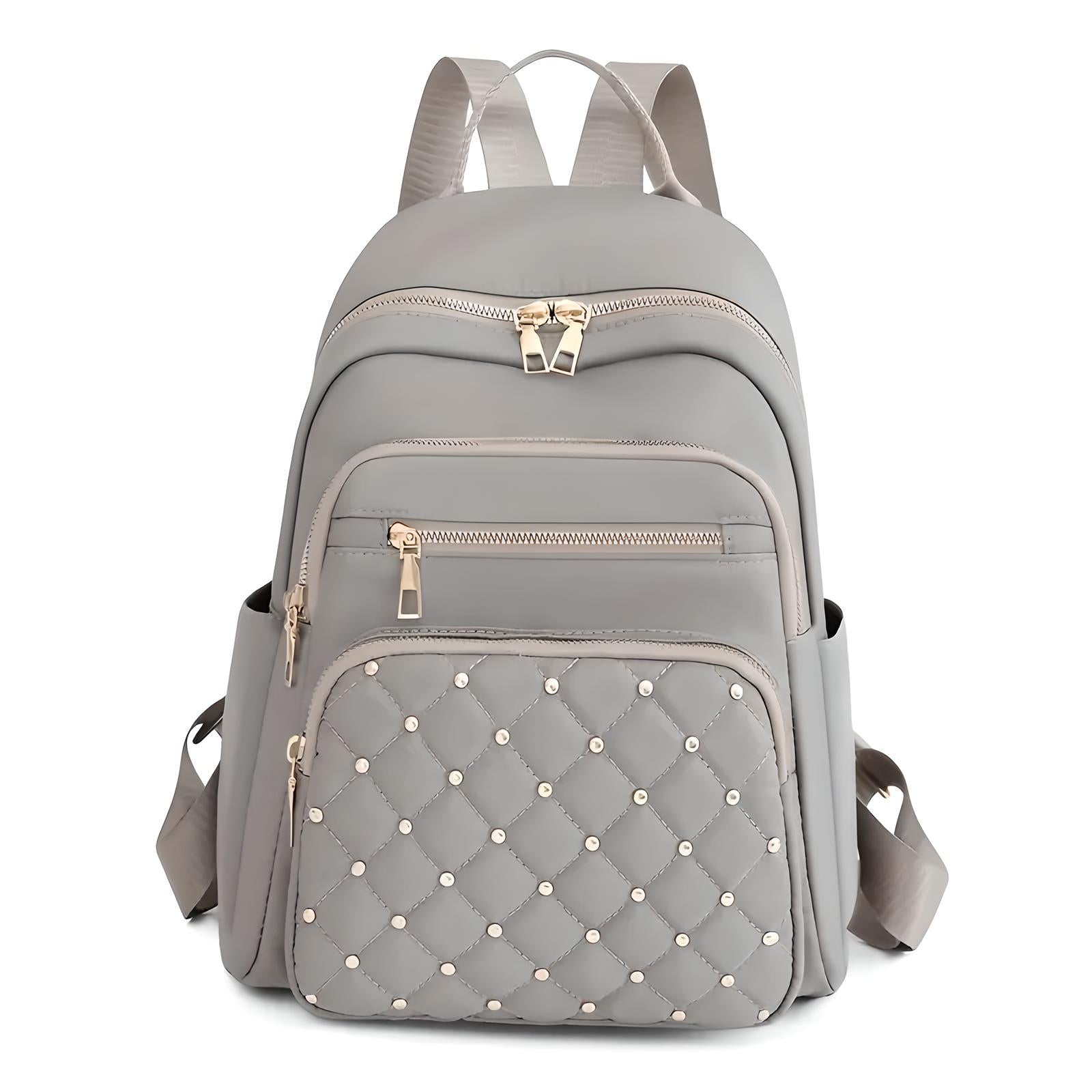 Stylish gray backpack with quilted front pocket, gold zippers, and multiple compartments. Perfect for travel, school, or daily use. Fashionable and functional.