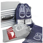 Travel shoe bags with drawstring closure, featuring sneaker design, displayed with a silver suitcase. Ideal for organized packing and shoe protection.