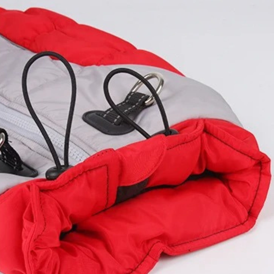 Red and gray insulated dog jacket with adjustable elastic cords and metal loops, designed for warmth and comfort. Ideal pet winter apparel.