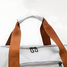 White duffel bag with brown handles and black zippers, featuring a sleek design. Perfect for travel, gym, or weekend trips. Durable and stylish accessory.