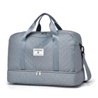 Gray quilted travel duffel bag with dual handles, detachable shoulder strap, and bottom compartment. Ideal for weekend trips and gym use.