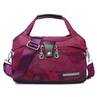 Stylish maroon women's handbag with adjustable shoulder strap, front zipper pocket, and decorative metal accents. Perfect for fashion-forward accessories.