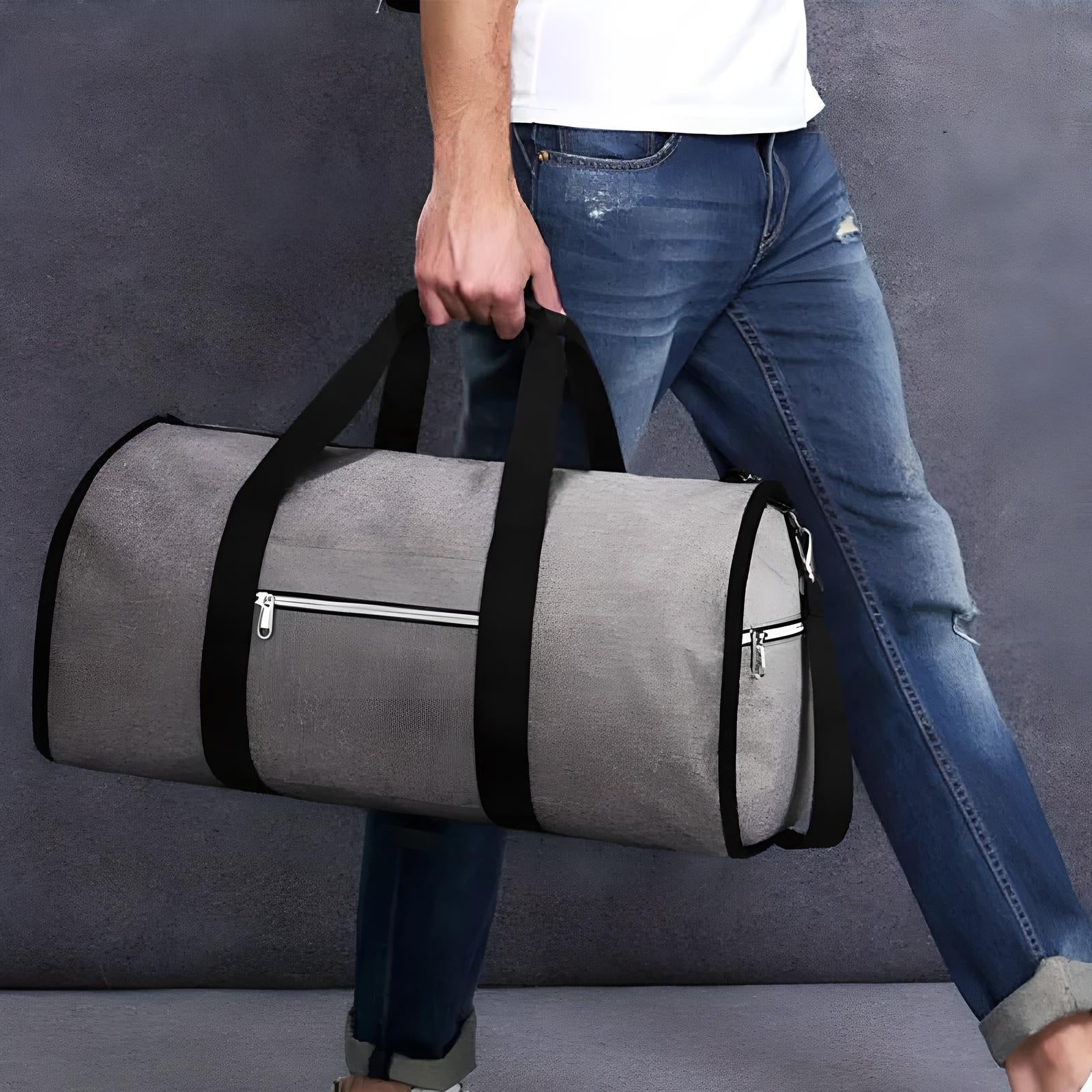 Man carrying a stylish gray duffel bag with black straps and zipper pocket, wearing casual jeans and white shirt. Perfect for travel or gym use.