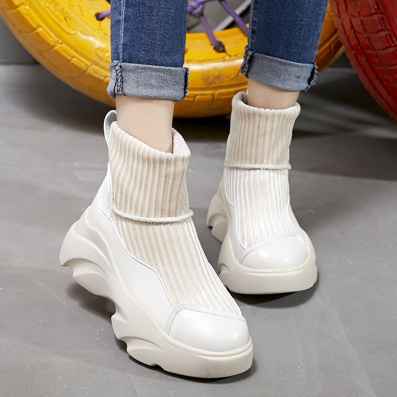 White chunky platform sneakers with ribbed sock design, worn with rolled-up jeans. Trendy women's footwear, casual street style fashion.