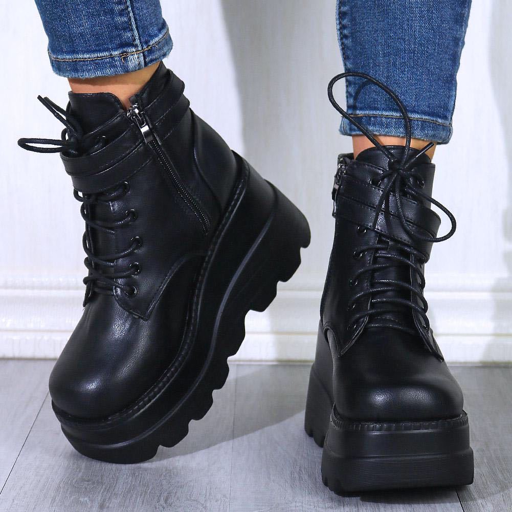 Black platform combat boots with chunky soles and lace-up design, paired with blue jeans. Trendy women's footwear for edgy fashion style.