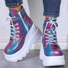 Colorful holographic platform boots with white laces and side zippers, worn with jeans. Trendy women's fashion footwear, chunky sole design.