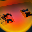 Two colorful abstract art pieces on a wall, featuring cartoon characters with expressive faces, illuminated by warm ambient lighting.