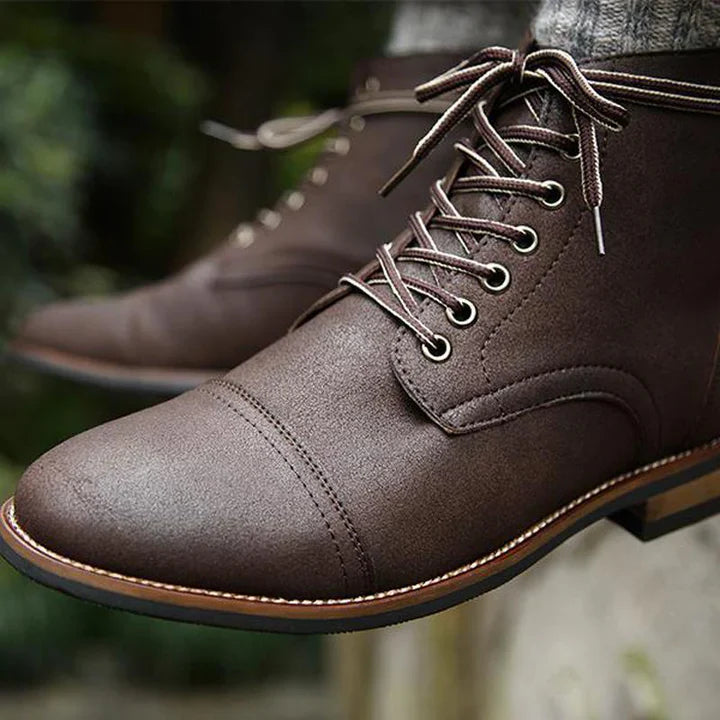 Brown leather lace-up boots with cap toe design, featuring detailed stitching and metal eyelets. Perfect for men's fashion and outdoor wear.