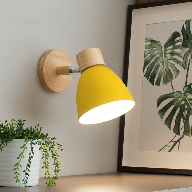 Yellow wall-mounted lamp with wooden accents, illuminating a modern interior. Stylish lighting fixture next to a framed botanical print and potted plant.