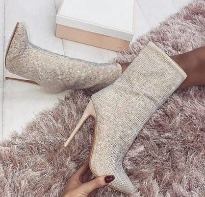 Sparkly high-heeled boots on a plush pink rug, featuring a shimmering design and stiletto heels, perfect for fashion-forward footwear enthusiasts.