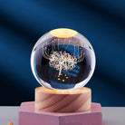 Crystal ball with intricate dandelion design on wooden base, illuminated against a dark blue background. Perfect for home decor and gift ideas.