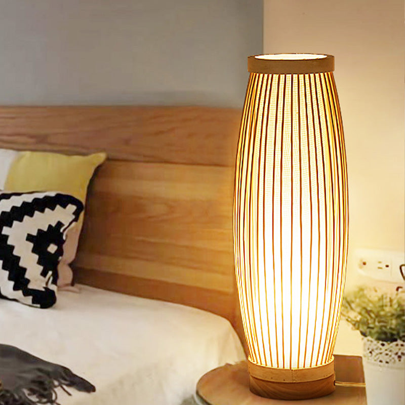 Modern bamboo table lamp with warm light on a wooden nightstand beside a bed, enhancing bedroom decor. Cozy lighting, minimalist design.