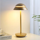 Modern gold table lamp with dome shade, LED lighting, and sleek design on a bedside table. Ideal for contemporary home decor and ambient lighting.