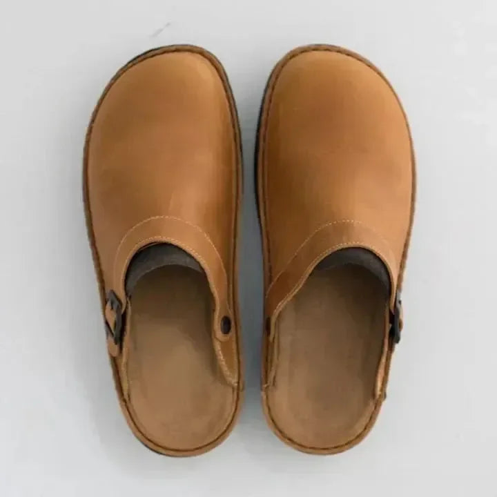 Brown leather slip-on clogs with buckle detail, top view. Comfortable footwear for casual wear. Durable, stylish shoes for men and women.