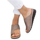 Women's beige open-toe slip-on sandals with textured design, paired with white rolled-up pants. Comfortable summer footwear, casual style.