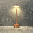 Modern copper LED table lamp on textured gray surface, minimalist design, energy-efficient lighting, home decor, contemporary style.