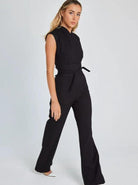 Woman in a stylish black jumpsuit with a tie waist, walking confidently. Fashionable outfit for modern women. Perfect for casual or formal occasions.