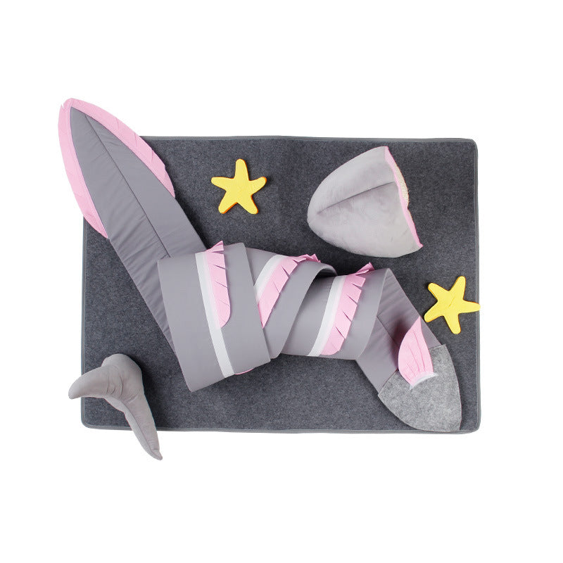 Gray and pink shark tail blanket on a gray mat with yellow starfish pillows, perfect for kids' bedroom decor or cozy lounging.