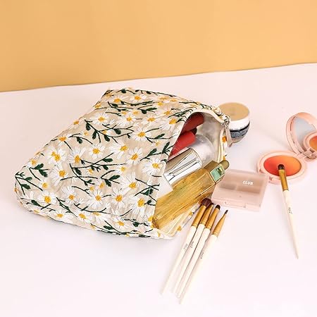 Floral makeup bag with daisy pattern, filled with cosmetics including brushes, lipstick, and compact powder on a beige background. Perfect for travel.