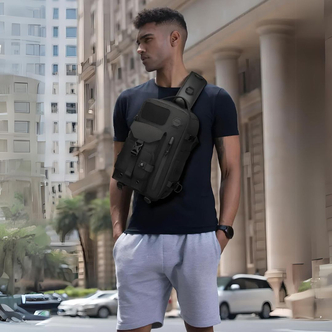 Man wearing a black crossbody tactical bag in urban setting; stylish, functional design ideal for travel and everyday use.