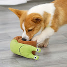 Corgi puppy playing with a green snail-shaped plush toy on a wooden floor. Cute dog, pet toy, playful puppy, indoor pet activity.