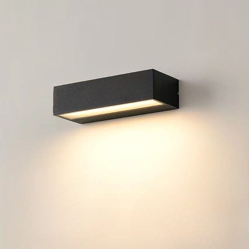 Modern black rectangular wall sconce with LED lighting, mounted on a beige wall, ideal for contemporary home decor and energy-efficient illumination.