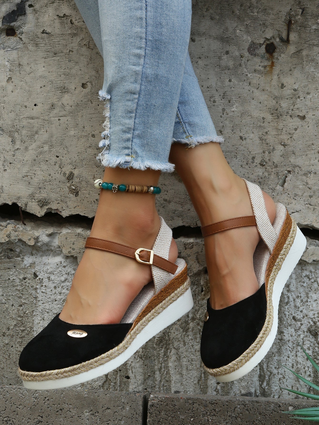 Women's black espadrille wedge sandals with ankle strap, paired with frayed hem jeans. Stylish summer footwear, casual fashion, boho chic.