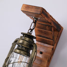 Rustic wall sconce with vintage lantern design, featuring a weathered metal finish and wooden mount. Ideal for farmhouse or industrial decor.