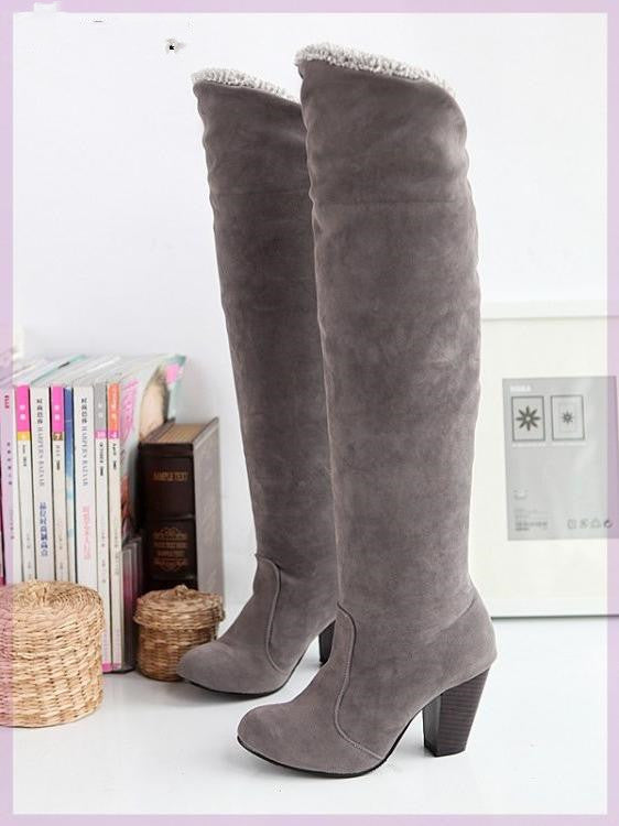 Gray suede knee-high boots with block heels, featuring a cozy fur lining. Stylish winter footwear for women, perfect for fashion-forward outfits.