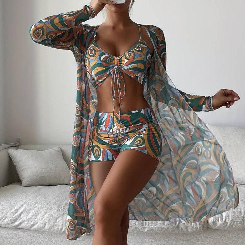 Woman in colorful geometric print bikini and sheer cover-up, standing indoors. Fashionable swimwear, summer style, trendy beachwear outfit.