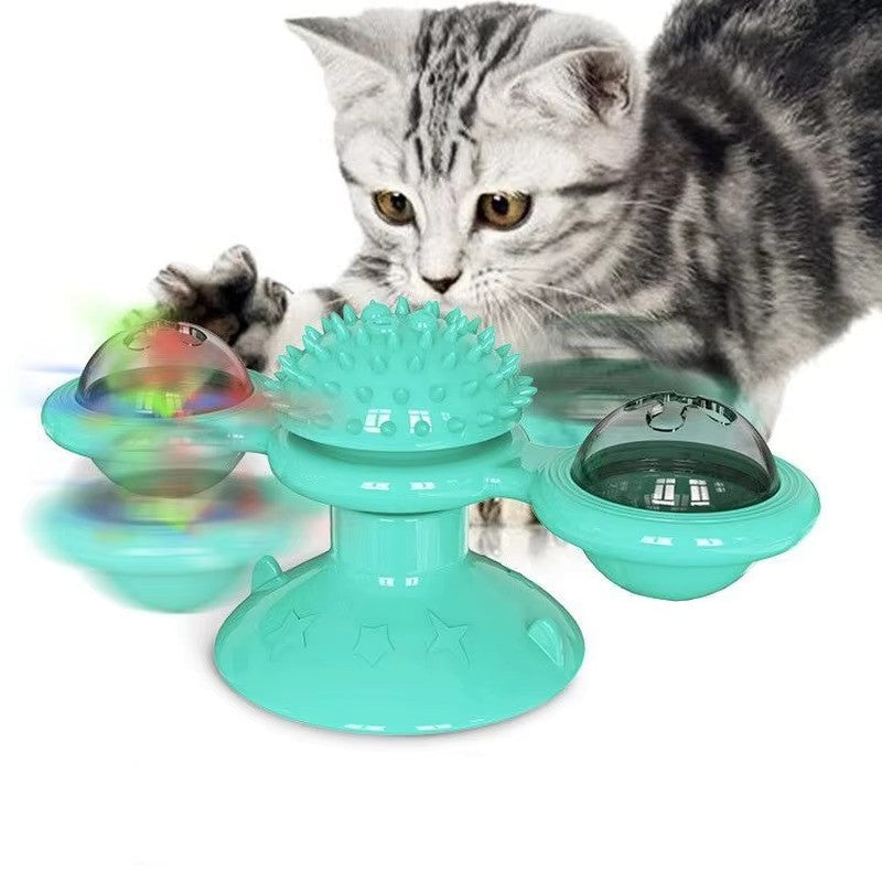 Cat playing with interactive spinning toy; teal color, suction base, rotating balls, and textured center. Ideal for pet entertainment and exercise.