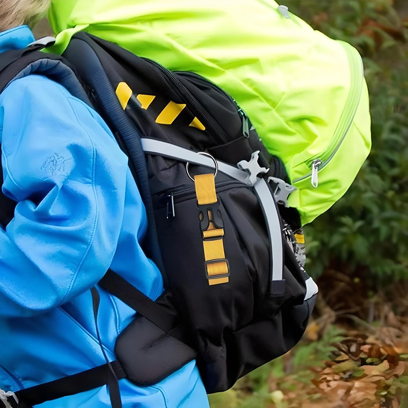 Hiking backpack with neon green cover and black straps, featuring a yellow carabiner clip, worn by a person in a blue jacket on a forest trail.