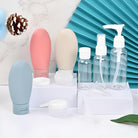 Travel-sized silicone toiletry bottles and clear pump dispensers on a white surface, ideal for cosmetics and skincare. Eco-friendly travel accessories.