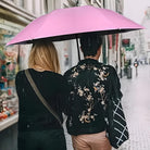 Two people walking under a pink umbrella on a rainy city street, wearing stylish jackets. Urban fashion, rainy day, city life.