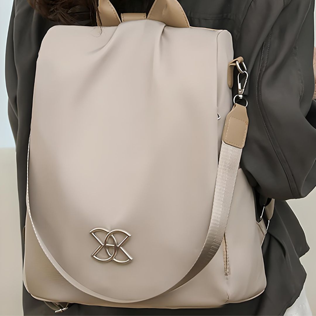 Beige leather backpack with silver logo, adjustable straps, and sleek design, ideal for fashion-forward travelers and daily commuters.