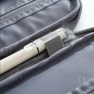 Close-up of a sleek gray travel organizer with a pen holder, showcasing a white pen secured inside. Ideal for efficient travel storage solutions.