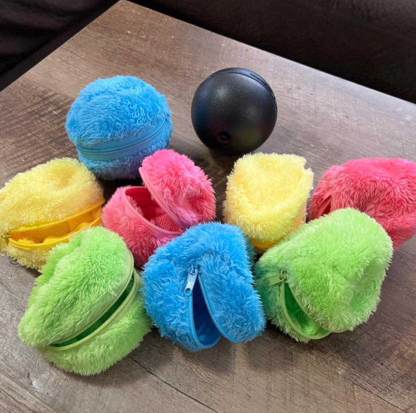 Colorful plush zipper pouches in blue, yellow, pink, and green on a wooden table, with a black stress ball. Fun, vibrant storage accessories.