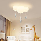 Modern children's room with cloud ceiling light fixture featuring hanging animal figures, crib, giraffe decor, and cozy ambiance.