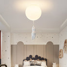 Modern kids' room with playful ceiling light fixture shaped like a hanging figure, star-patterned wallpaper, and cozy bed. Stylish children's decor.