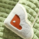 Green quilted blanket with soft, fluffy texture featuring a heart-shaped patch. Cozy bedding, plush comforter, warm home decor accessory.