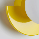 Modern yellow wall sconce with geometric design, featuring a semi-circular shape and glossy finish. Contemporary lighting fixture for home decor.