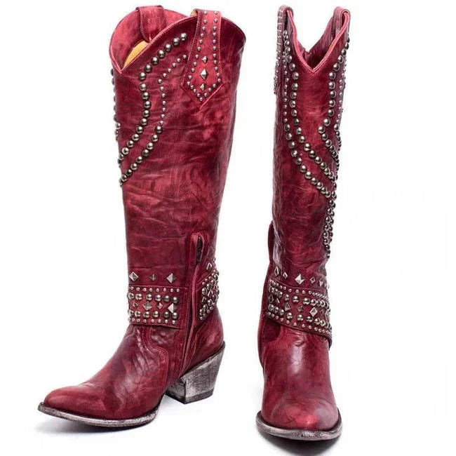 Red leather cowboy boots with silver stud embellishments, featuring a pointed toe and stacked heel. Stylish Western footwear for women.