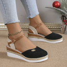 Women's black espadrille wedge sandals with ankle strap, paired with light blue jeans. Stylish summer footwear, casual fashion, comfortable design.