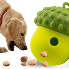 Dog playing with green acorn-shaped treat dispenser toy, surrounded by scattered kibble. Interactive pet toy, dog enrichment, durable chew toy.